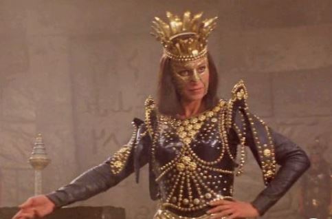 Una reina chunga &iquest;medieval? con una especie de m&aacute;scara dorada que le cubre la mitad de la cara, en pose yass queen